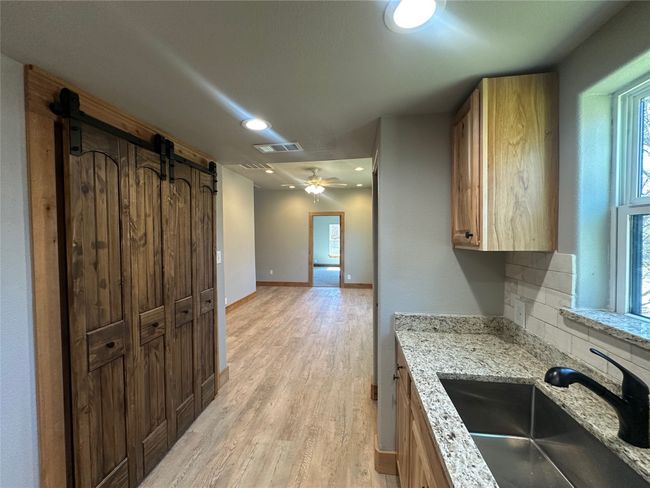 Kitchen with a sink, a barn door, visible vents, light wood-style floors, and decorative backsplash | Image 19