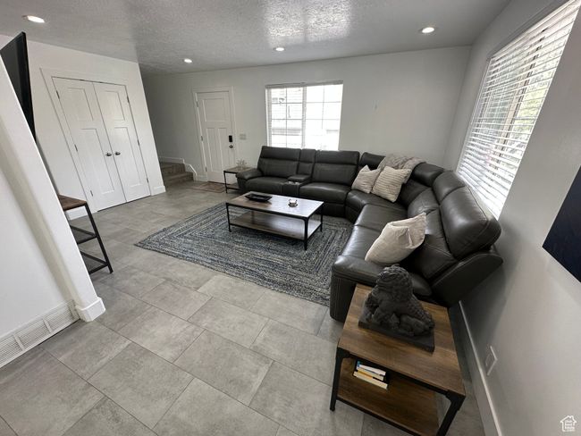 Living room featuring baseboards, recessed lighting, a textured ceiling, and stairway | Image 6