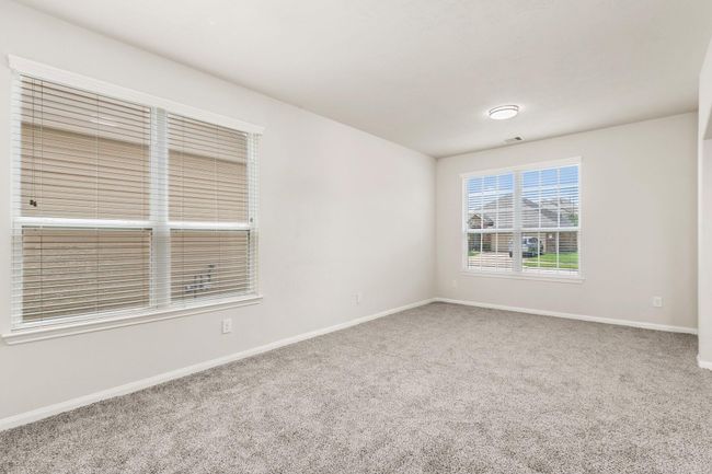 Bright and airy room with neutral walls and carpet, featuring large windows with blinds that offer ample natural light. | Image 6
