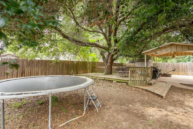 Fenced backyard with a storage shed, a wooden deck, and a trampoline | Image 32