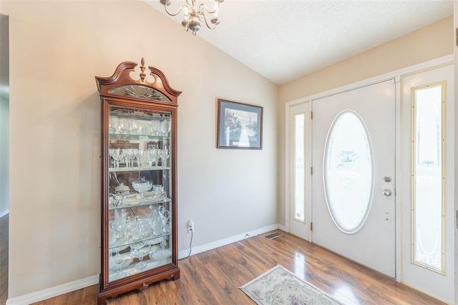 Foyer entrance featuring vaulted ceiling, wood finished floors, a chandelier, and baseboards | Image 9