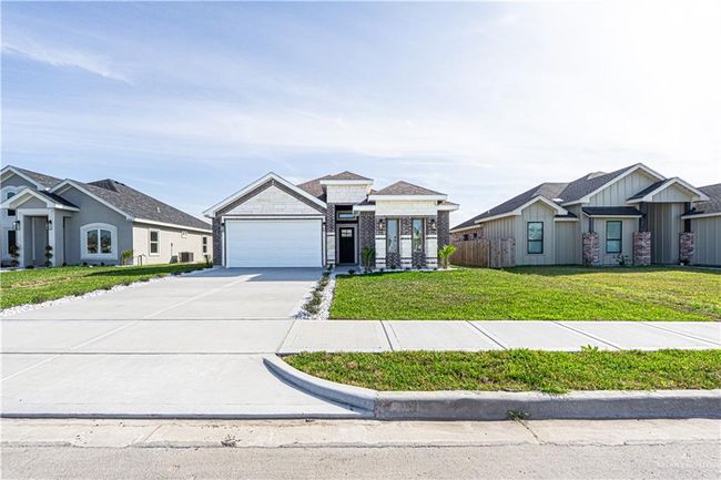 View of front of house featuring concrete driveway, an attached garage, fence, a front yard, and brick siding | Image 13