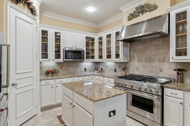 Kitchen featuring appliances with stainless steel finishes, extractor fan, ornamental molding, white cabinets, and tasteful backsplash | Image 8