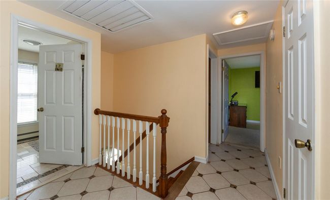Hallway with visible vents, attic access, an upstairs landing, a baseboard radiator, and baseboards | Image 28