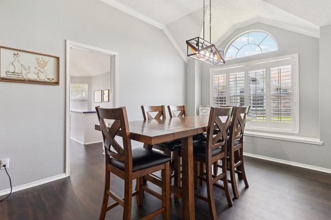 Dining room with vaulted ceiling, a chandelier, dark wood-style flooring, crown molding, and baseboards | Image 10