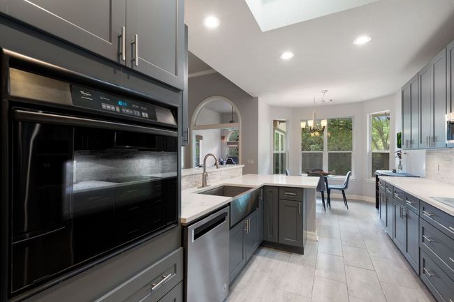 Kitchen with stainless steel dishwasher, a sink, an inviting chandelier, backsplash, and gray cabinetry | Image 15