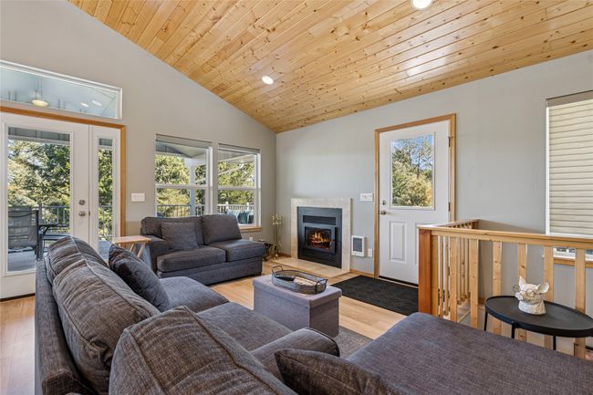 Living area featuring wood ceiling, a fireplace with flush hearth, wood finished floors, and plenty of natural light | Image 5