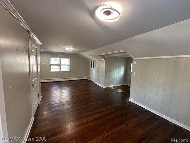 Bonus room with dark wood-style floors, baseboard heating, wooden walls, and lofted ceiling | Image 26
