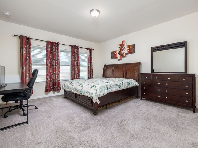 Bedroom with light colored carpet, a desk, and baseboards | Image 11