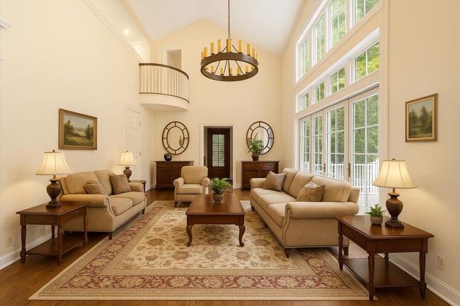 Living area featuring wood finished floors, baseboards, a chandelier, and high vaulted ceiling | Image 10