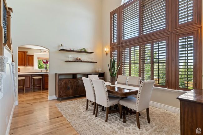 Dining area featuring a high ceiling, plenty of natural light, baseboards, and light wood-type flooring | Image 7