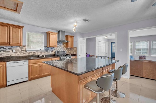 Kitchen featuring stainless steel gas range, white dishwasher, a sink, wall chimney exhaust hood, and a healthy amount of sunlight | Image 22