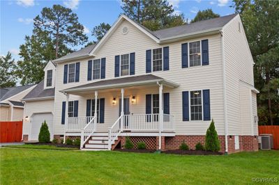 Colonial-style house with a porch, a garage, central AC unit, and a front yard | Image 3