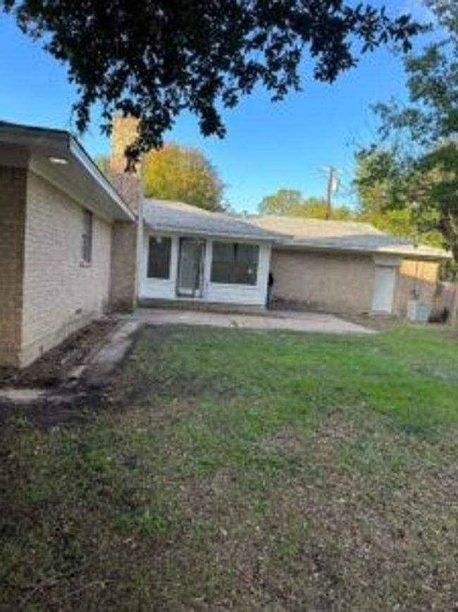Back of property featuring brick siding, a chimney, a yard, and a patio area | Image 4