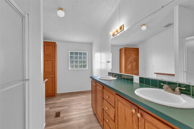 Bathroom featuring a textured ceiling, double vanity, and wood finished floors | Image 28