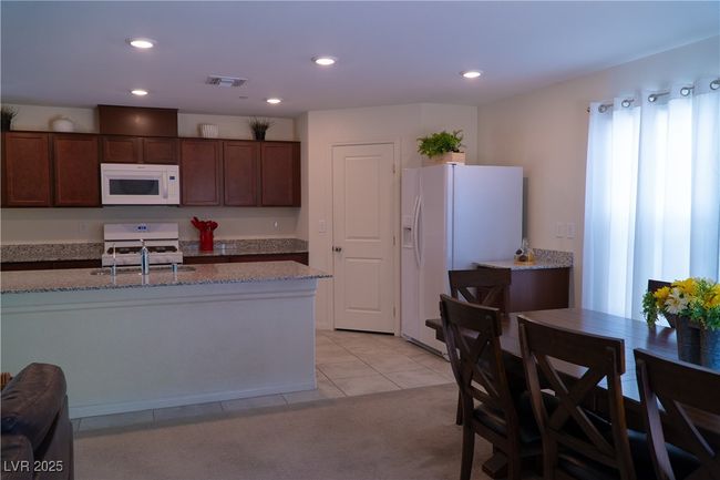 Kitchen featuring recessed lighting, visible vents, light stone counters, and white appliances | Image 24