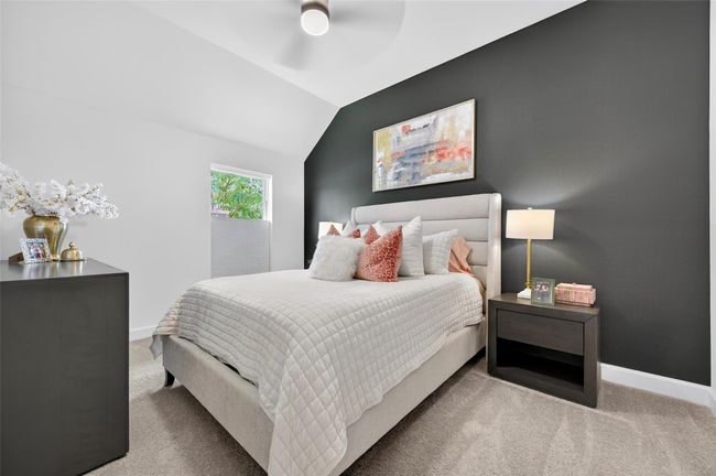 Comfortable secondary bedroom with high ceiling, neutral carpet, and a bold accent wall that adds contrast and style. A bright window offers natural light and backyard views. | Image 23