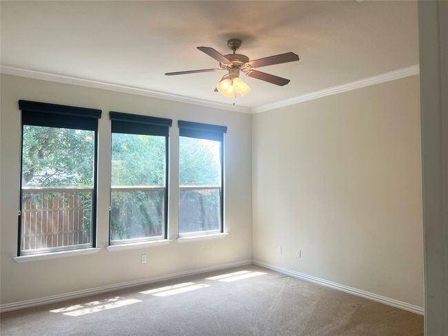 Empty room with ornamental molding, carpet, baseboards, and ceiling fan | Image 9