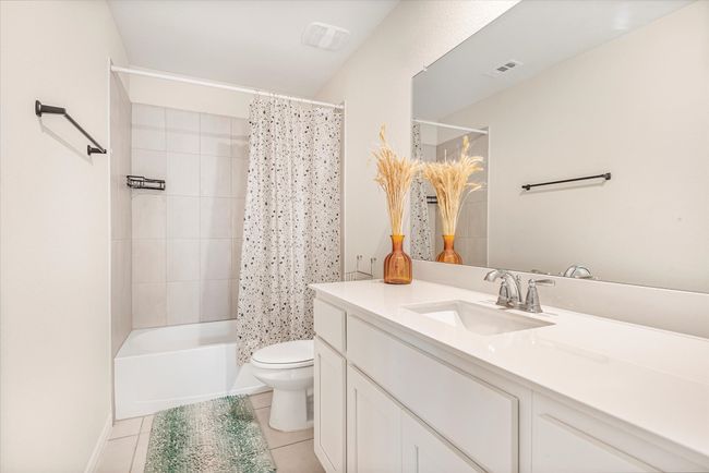 Bathroom with tile patterned flooring, toilet, shower / tub combo, visible vents, and vanity | Image 26