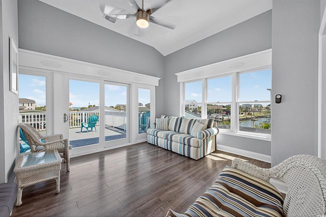 Living room with a water view, vaulted ceiling, dark wood-style flooring, and a ceiling fan | Image 18