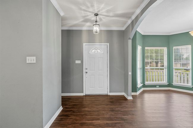 Foyer featuring dark wood-style floors, crown molding, and arched walkways | Image 16
