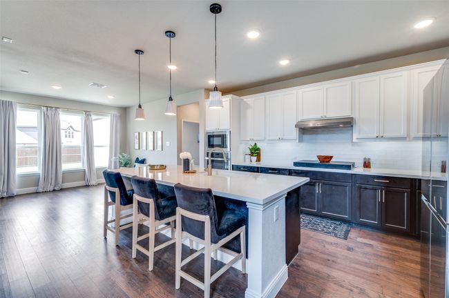 Kitchen featuring tasteful backsplash, light countertops, under cabinet range hood, stainless steel appliances, and dark wood-type flooring | Image 11