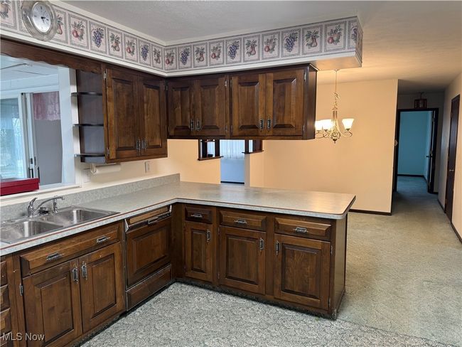 Kitchen featuring a peninsula, dishwasher, dark brown cabinets, and a sink | Image 17