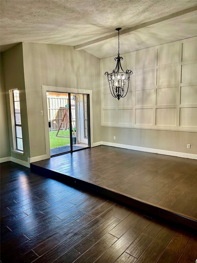 Big room with dark wood-style floors, a chandelier, and a textured ceiling | Image 5