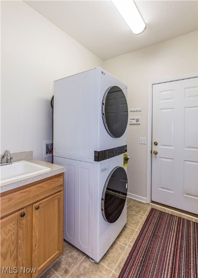 Clothes washing area with stacked washer and dryer and sink | Image 13
