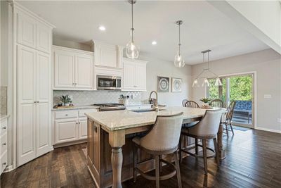 Kitchen with white cabinetry, stainless steel appliances, a center island with sink, and dark hardwood / wood-style flooring | Image 1