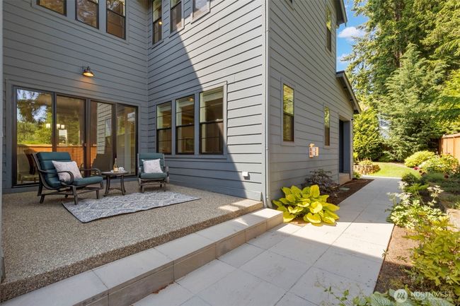 This inviting side yard features a charming patio just off the dining room—an ideal spot for quiet morning coffee or evening conversation. Surrounded by lush landscaping and easy-care pathways, it’s a private extension of the home’s indoor-outdoor lifestyle. | Image 40