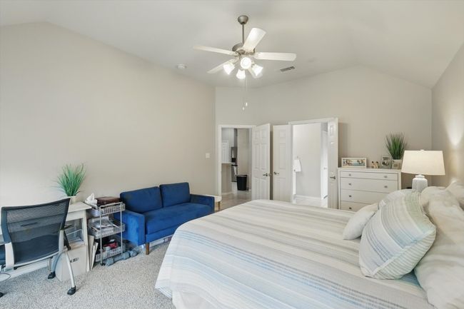 Carpeted bedroom featuring ceiling fan, vaulted ceiling, and visible vents | Image 23