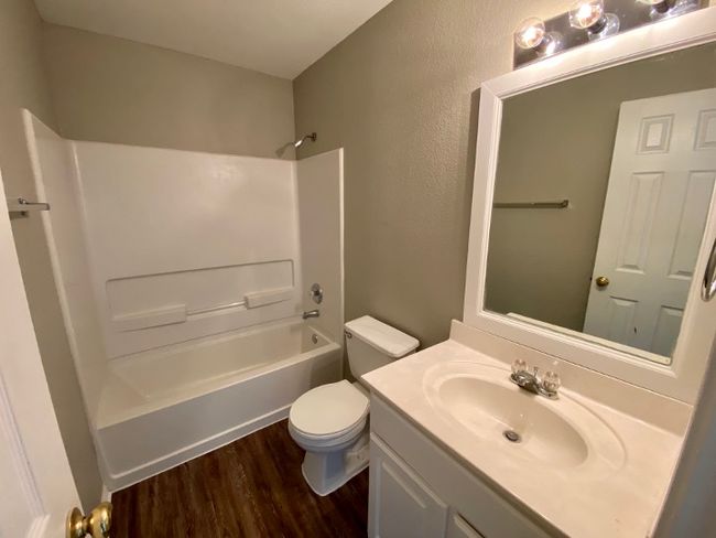 Bathroom with wood finished floors, vanity, shower / bathtub combination, and a textured wall | Image 17