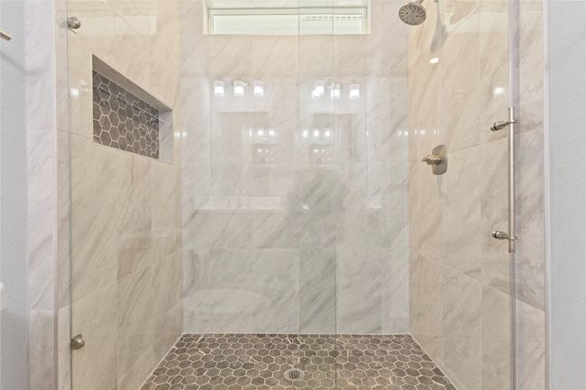 A stunning primary bathroom with a sleek double vanity and a luxurious walk-in shower—front view highlighting its spacious design and natural light. | Image 23