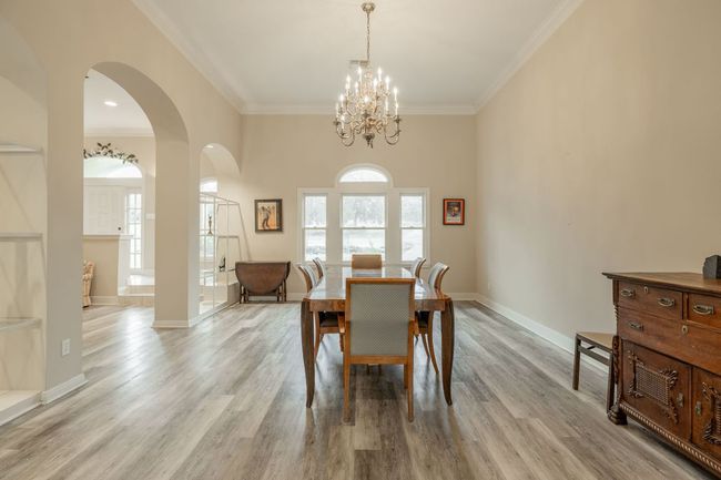 Dining room featuring ornamental molding, arched walkways, a chandelier, light wood-style flooring, and baseboards | Image 10