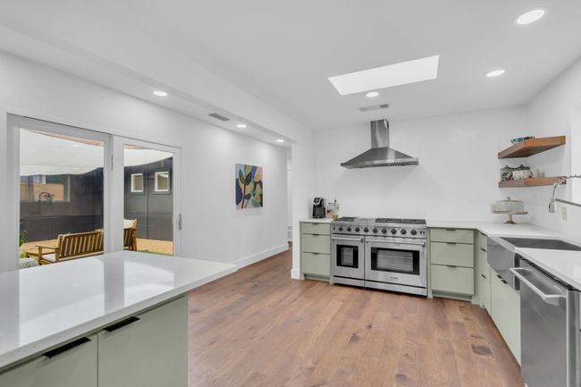 Kitchen with wall chimney range hood, appliances with stainless steel finishes, a skylight, visible vents, and green cabinets | Image 20