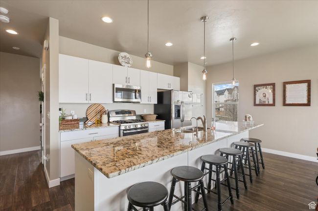 Kitchen featuring a kitchen island with sink, a sink, baseboards, dark wood-type flooring, and appliances with stainless steel finishes | Image 13