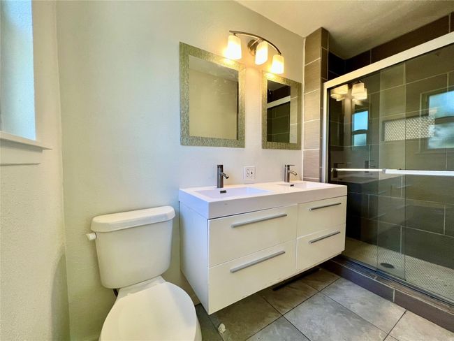 Full bathroom with double vanity, toilet, a stall shower, and tile patterned flooring | Image 20