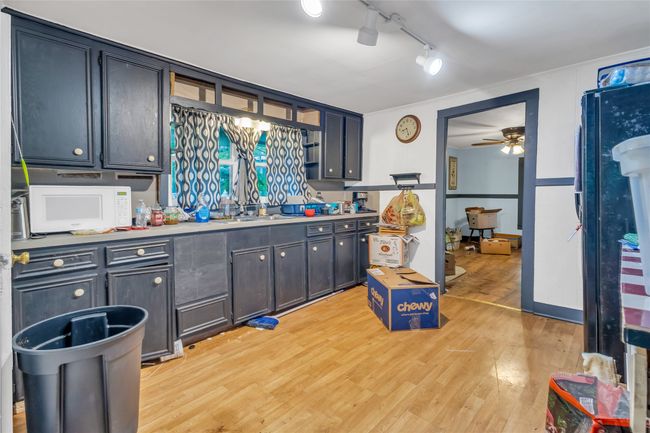Kitchen featuring white microwave, light wood-type flooring, ceiling fan, rail lighting, and light countertops | Image 5