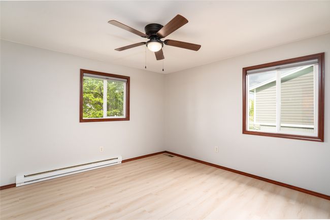 Spare room featuring a baseboard heating unit, light wood finished floors, baseboards, and ceiling fan | Image 13