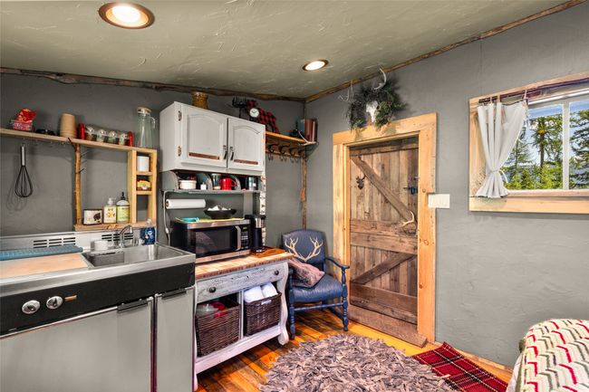 Cabin Studio Kitchenette featuring stainless steel microwave, open shelves, wood finished floors, white cabinetry, and light countertops | Image 45