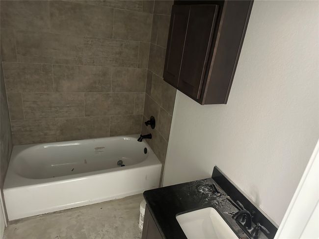 Full bath featuring concrete floors, vanity, and bathtub / shower combination | Image 5