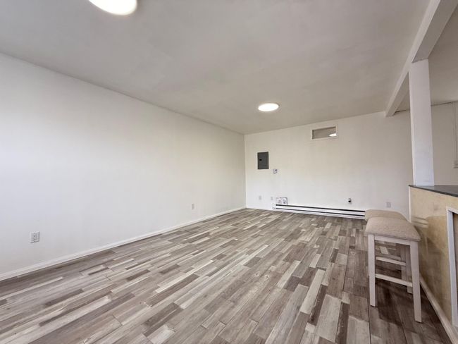 living room featuring electric panel, a baseboard heating unit, baseboards, and wood finished floors | Image 6
