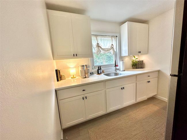 Kitchen featuring a sink, decorative backsplash, light countertops, white cabinets, and tile patterned flooring | Image 11