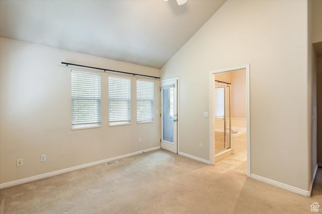Master Bedroom with light carpet, connected bathroom, and high vaulted ceiling | Image 18