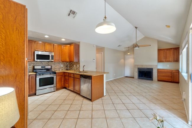 Spacious and modern kitchen features granite countertops with a spacious peninsula and a view to the living area for easy entertaining. | Image 12
