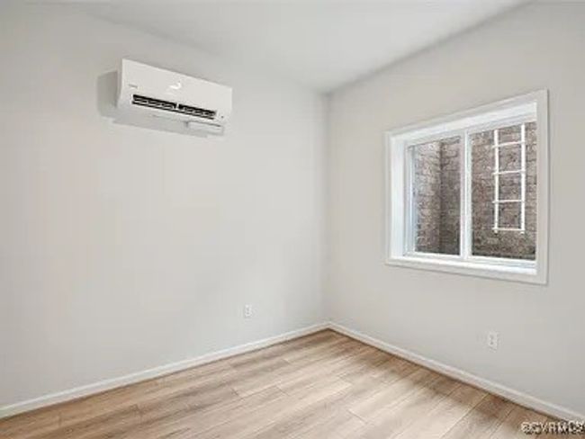 Empty room featuring a wall mounted air conditioner and light wood-style floors | Image 7