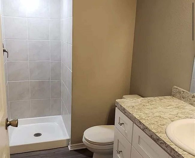 Bathroom with a tile shower, vanity, toilet, and wood finished floors | Image 10