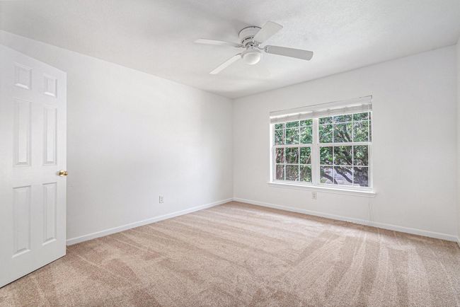 This bright, spacious bedroom features fresh carpeting, a ceiling fan, and a large window offering plenty of natural light. | Image 15