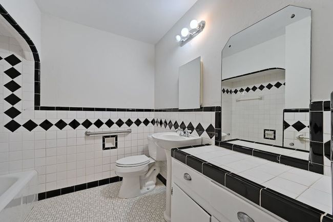 Bathroom featuring a wainscoted wall, toilet, a bathing tub, tile patterned floors, and tile walls | Image 13